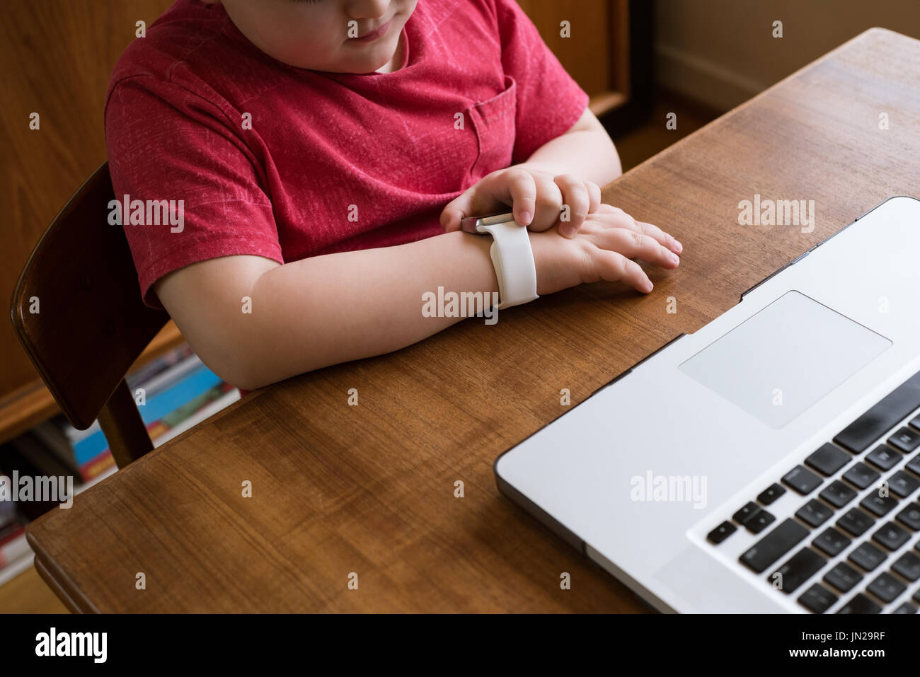 High angle view boy using smart watch while sitting by laptop at table Stock Photo