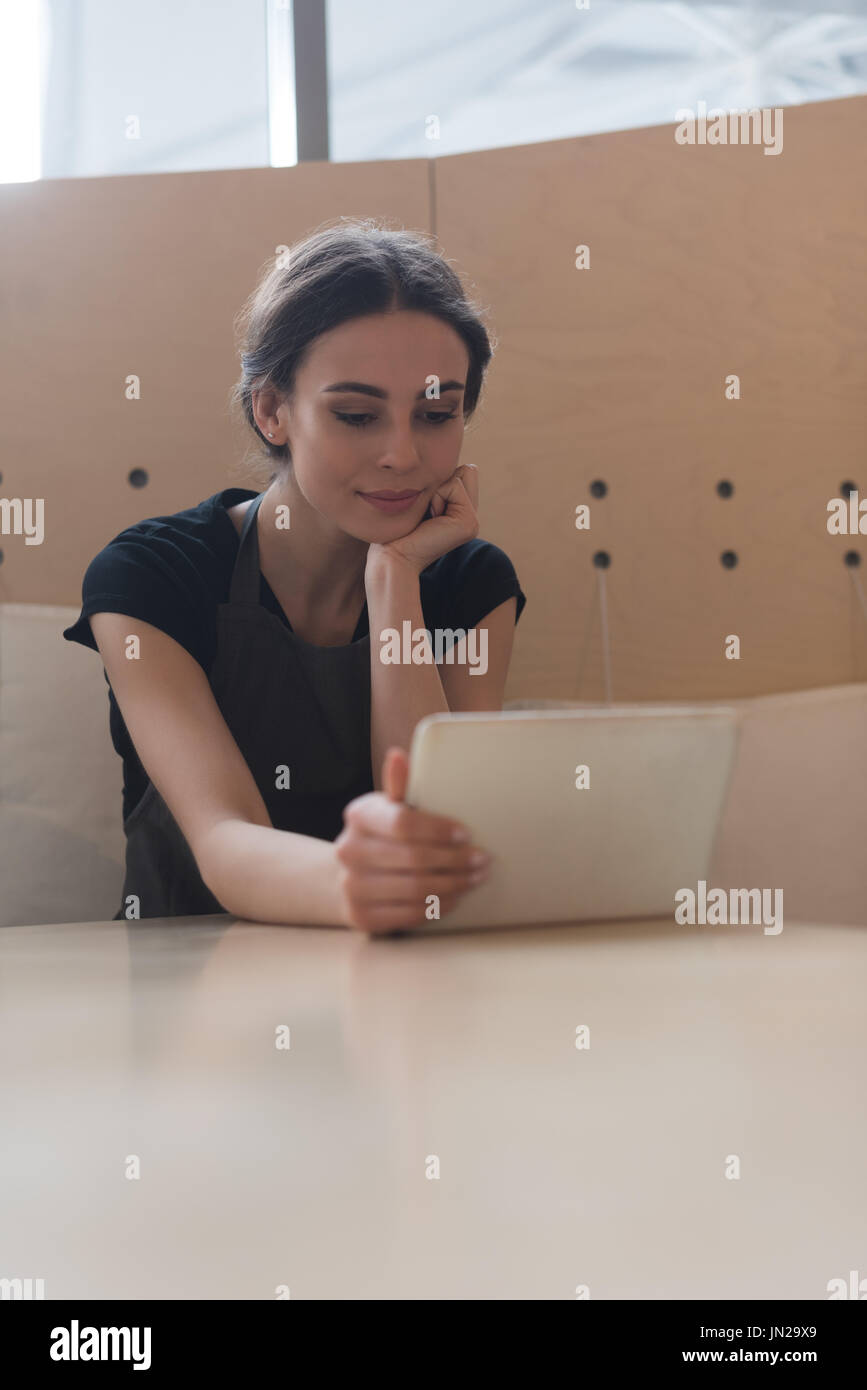 Female owner using digital tablet while sitting at table in cafe Stock Photo