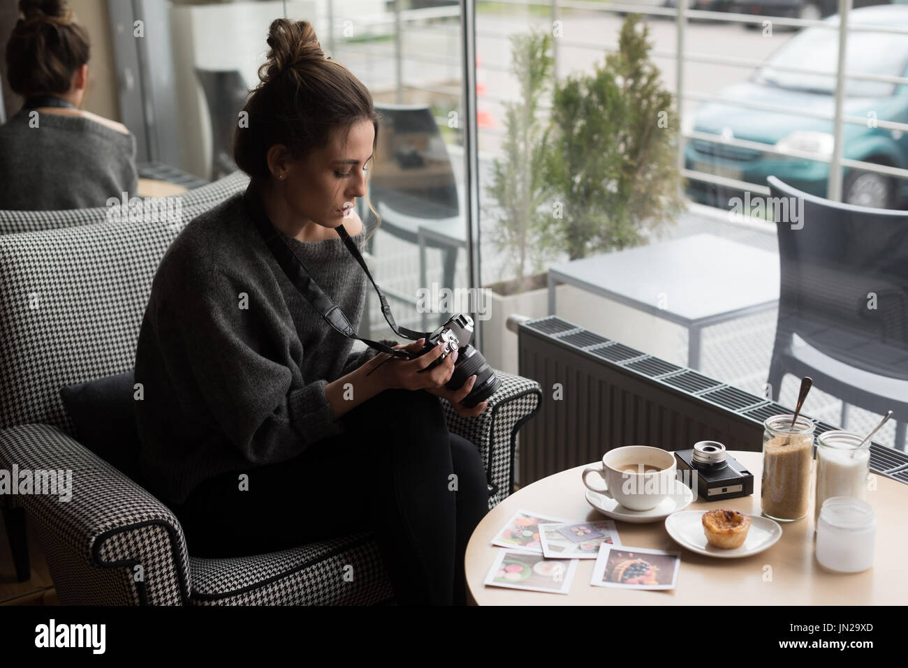 Young woman photographing coffee and photographs on table while sitting in cafe Stock Photo