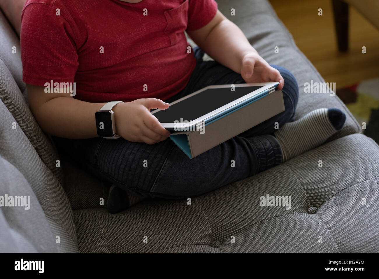 Low section of boy using tablet computer while sitting on sofe Stock Photo