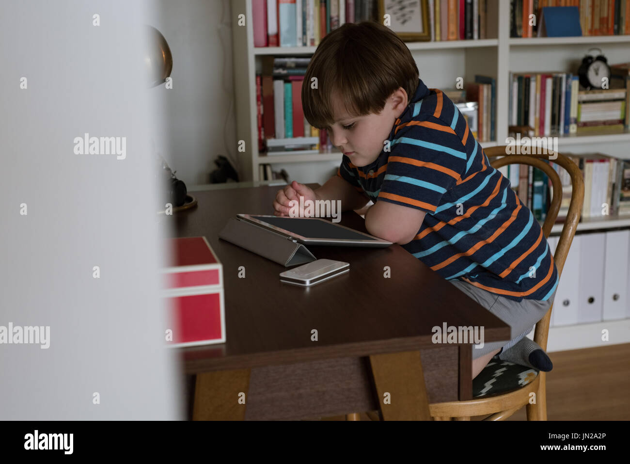 Side view of boy using digital tablet while sitting at table Stock Photo