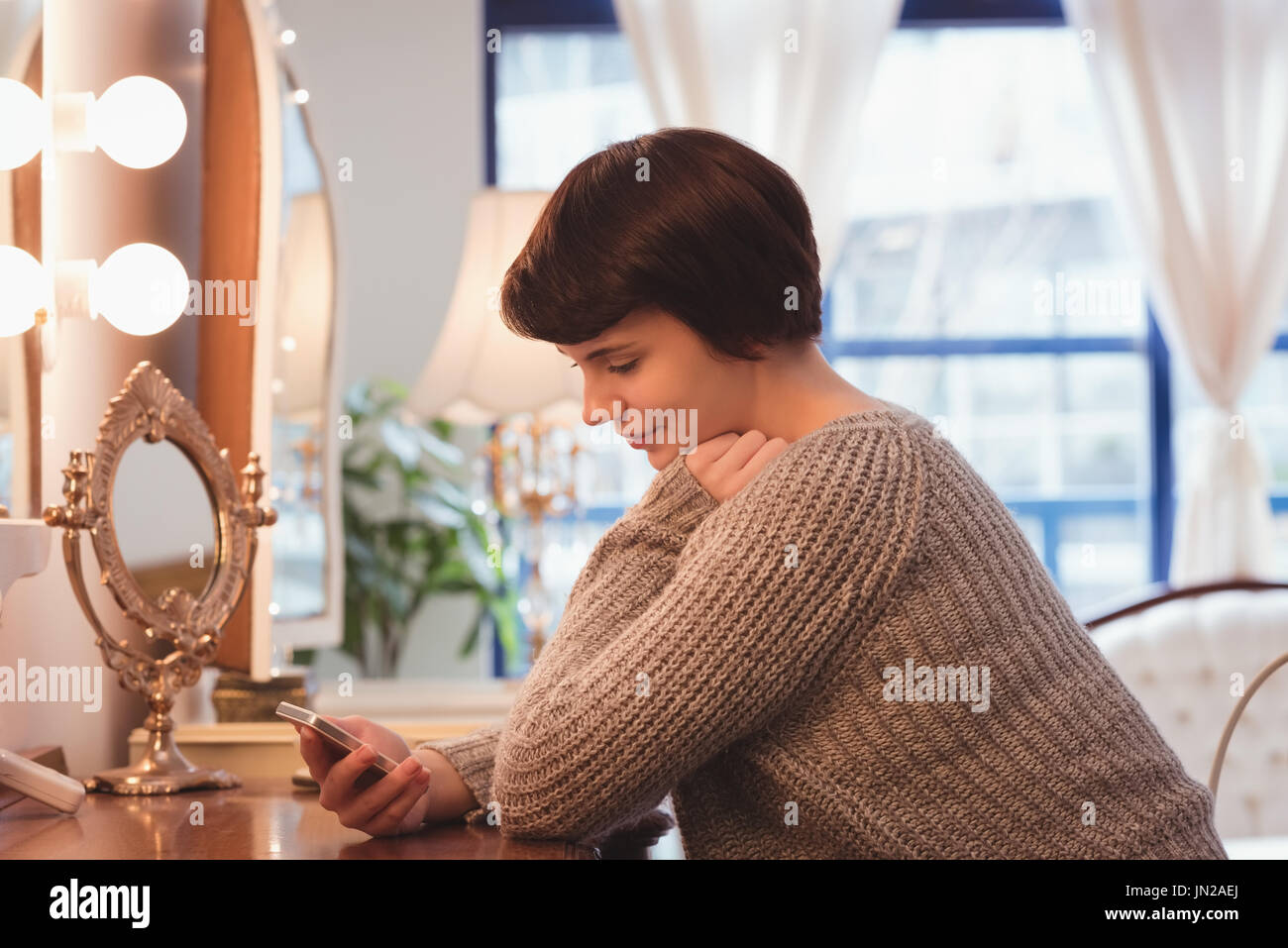 Young woman using mobile phone at home Stock Photo