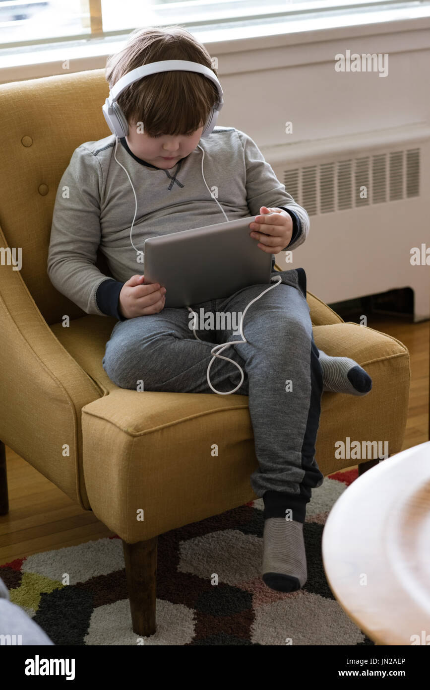 High angle view of boy wearing headphones while using tablet computer at home Stock Photo