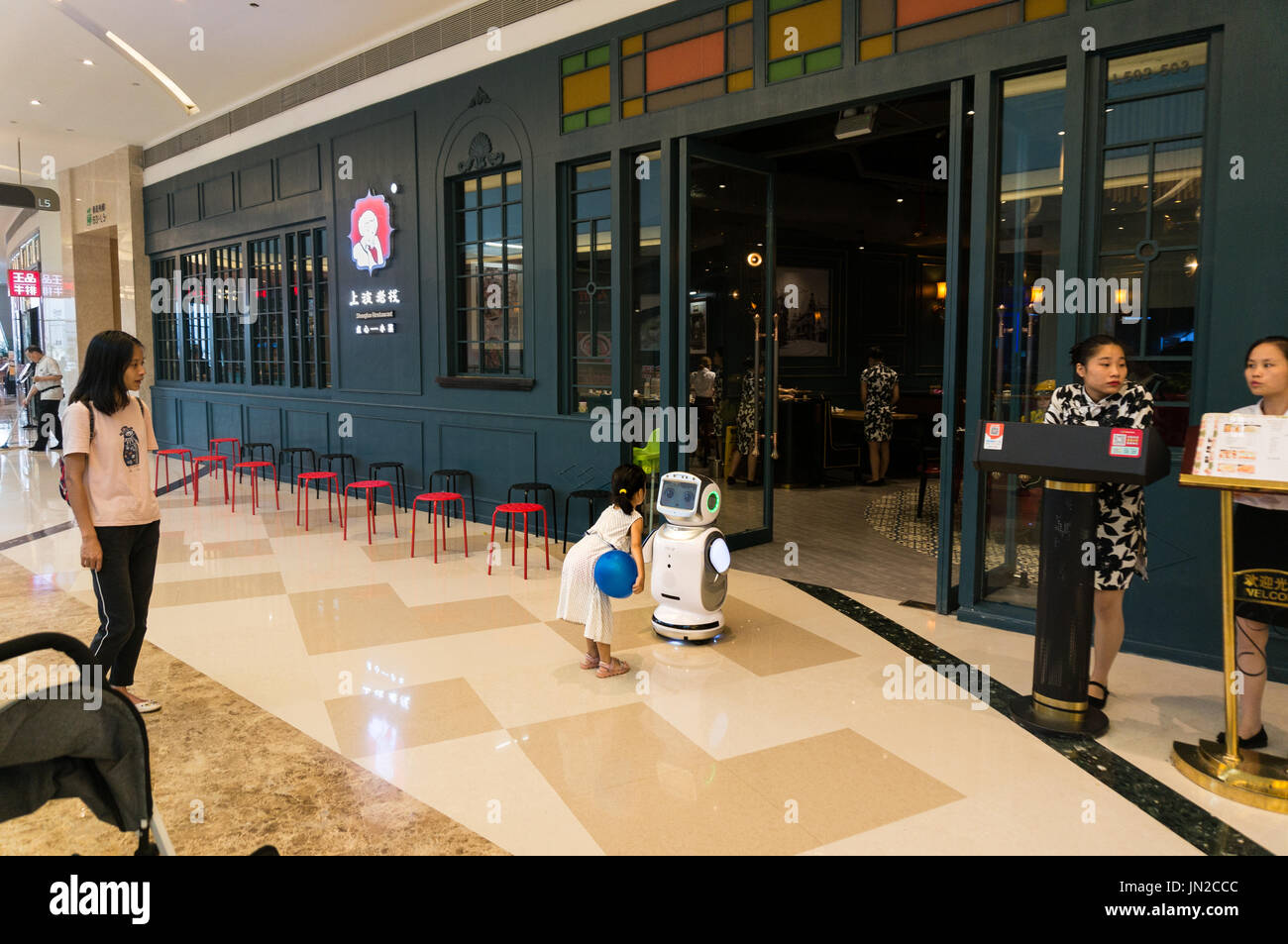 Young child curious about robot in front of restaurant in Shenzhen, China Stock Photo