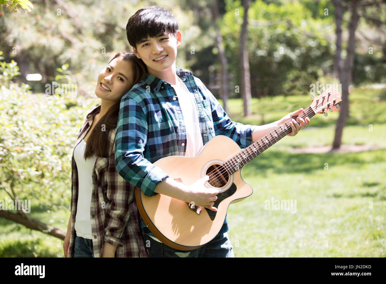 portrait of beautiful young wedding couple posing in outdoor photoshoot  playing guitar Stock Photo - Alamy