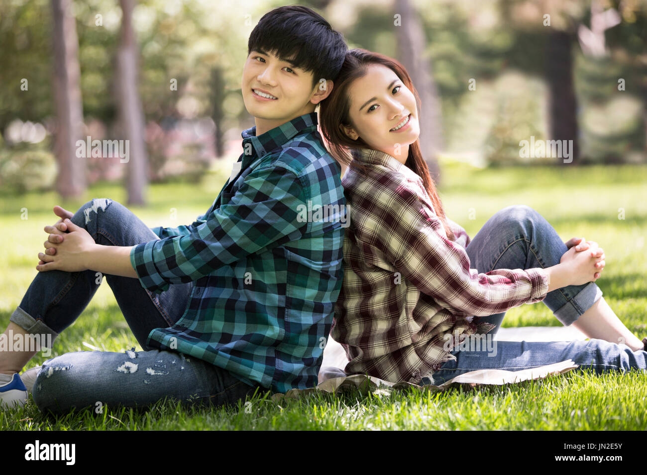 Cute asian couple sitting in the park smiling and looking at camera Stock  Photo - Alamy