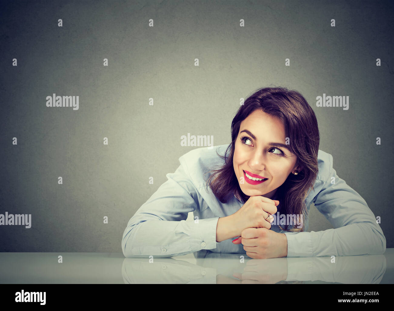 Thinking happy business woman sitting at desk Stock Photo