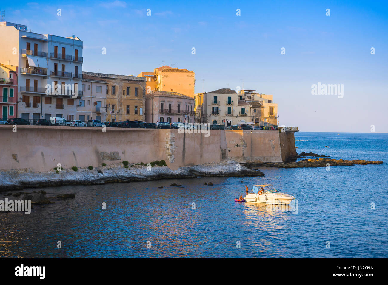Sicily bay, view at sunset of a family relaxing on a leisure boat in a bay to the south of Ortigia Island (Syracuse) Sicily, Stock Photo