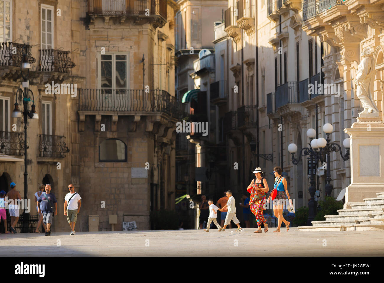 Women friends travel, view of two women tourists walking through the historic Piazza del Duomo in Ortigia, Syracuse (Siracusa), Sicily, Italy Stock Photo