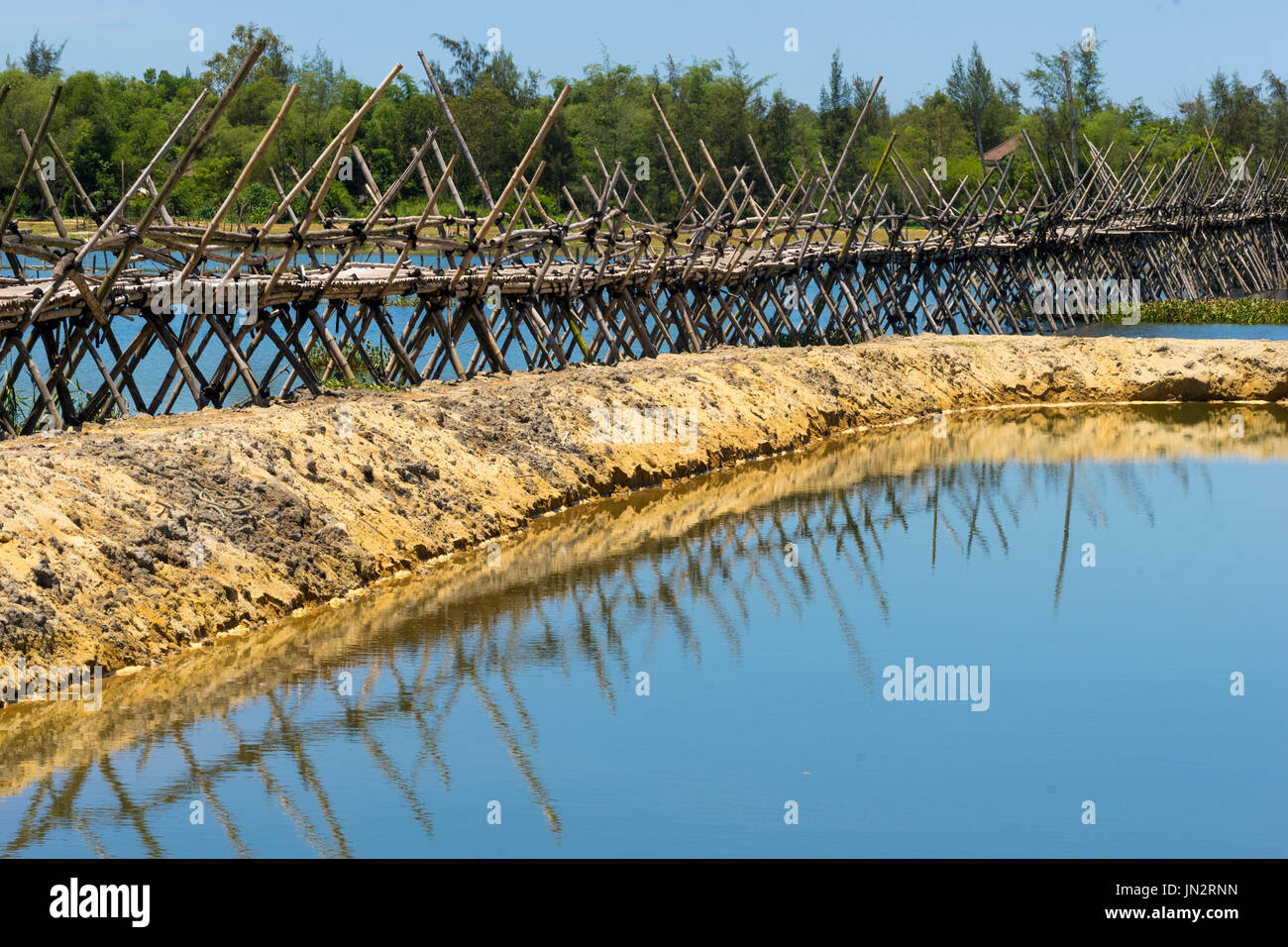 Traditional bamboo bridge spanning across lake near Hoi An, Vietnam Stock Photo