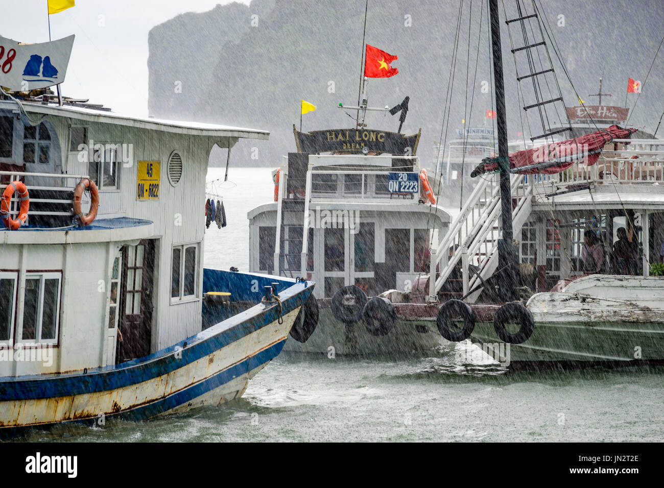 Junk boats taking tourists out to see Ha Long Bay despite heavy rain Stock Photo