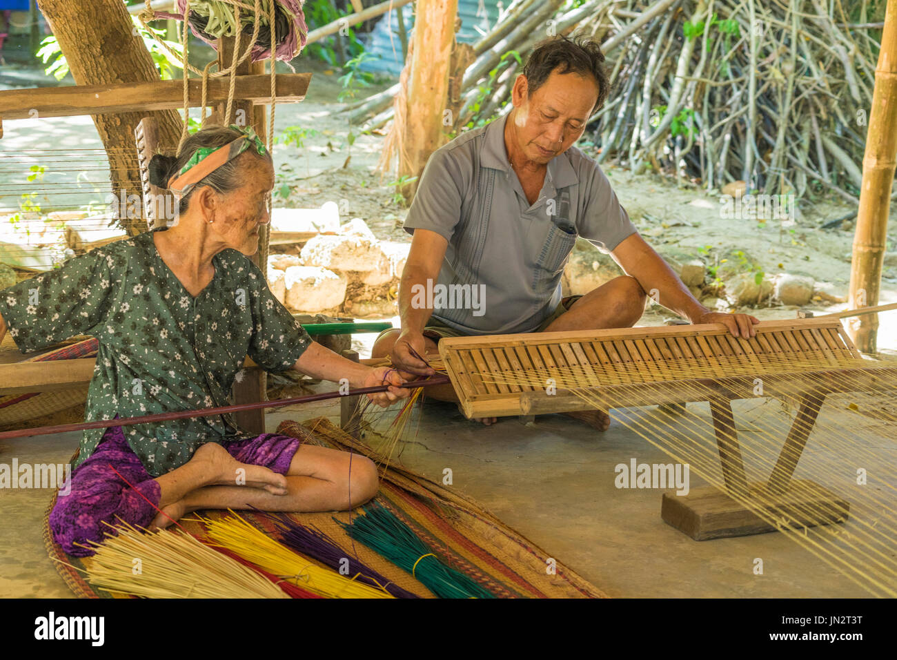 Vietnamese man and woman working together to make reed mat with a simple loom using traditional methods Stock Photo