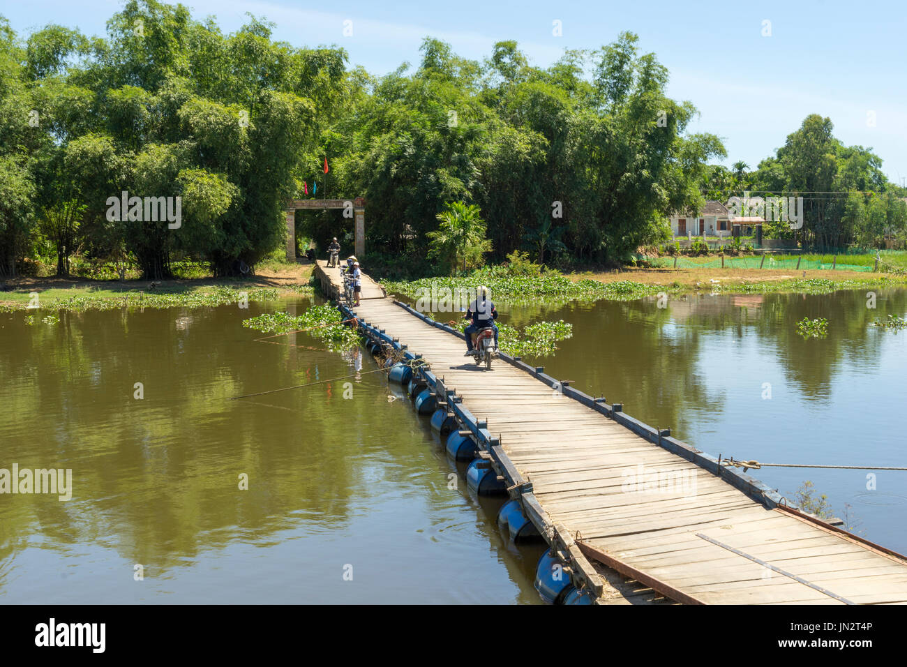 Moped riding across rustic floating bridge over Thu Bon River in rural Vietnam outside Hoi An Stock Photo