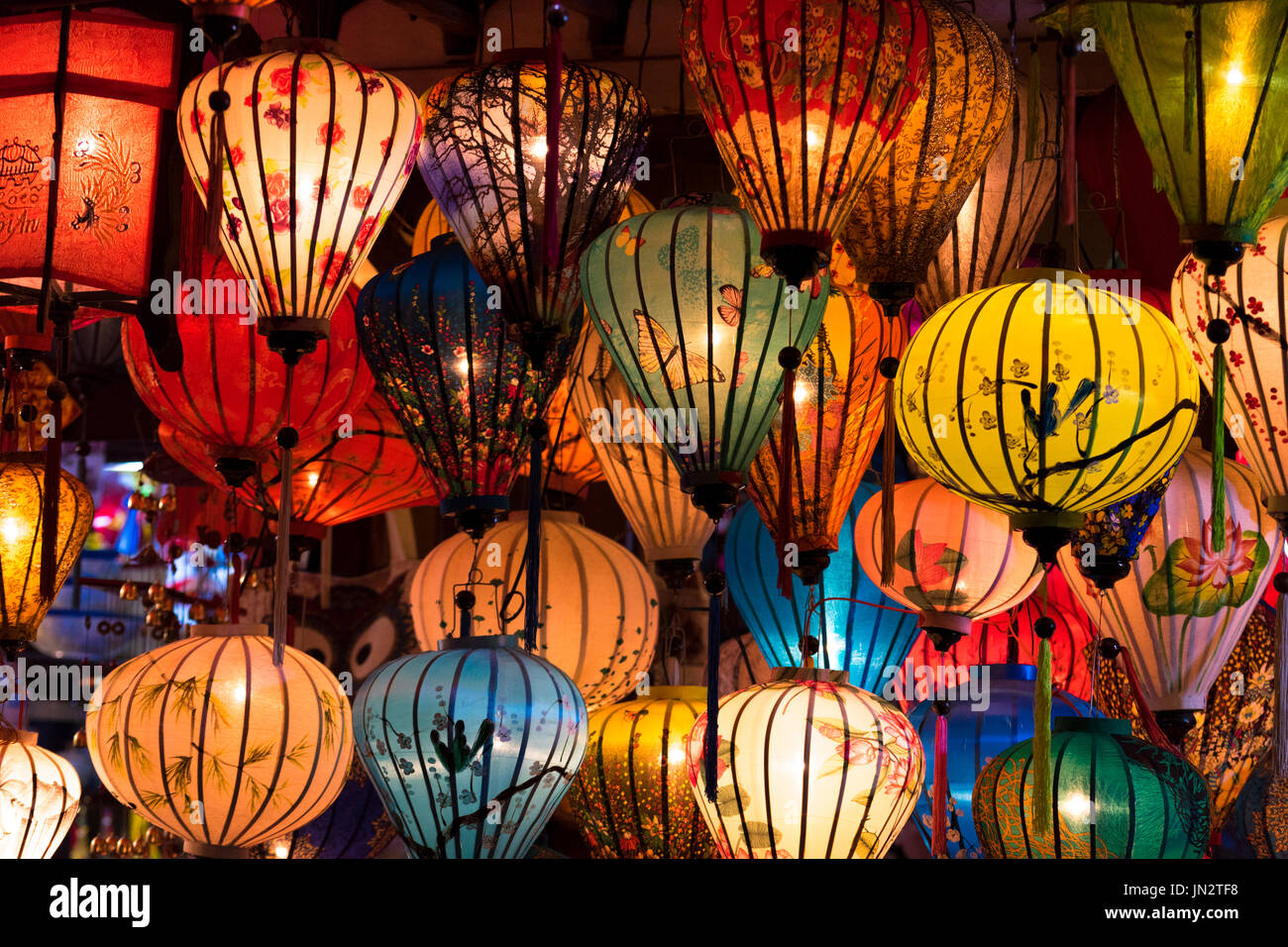 Many silk lanterns of various colors and designs hanging from a shop at night in Hoi An, Vietnam Stock Photo