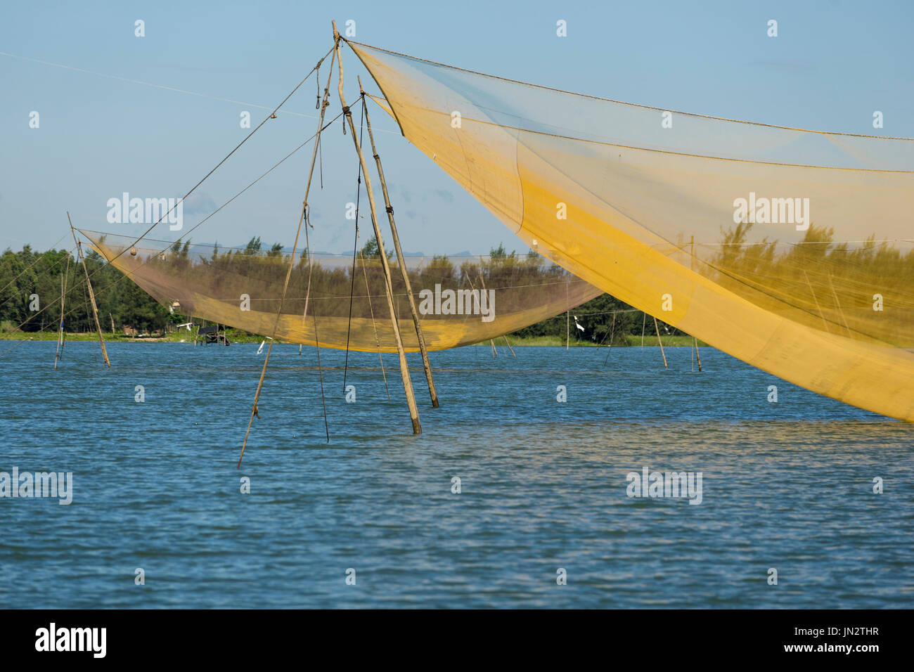 Giant fishing nets raised up and suspended on posts over Thu Bon River - traditional Vietnamese fishing method Stock Photo