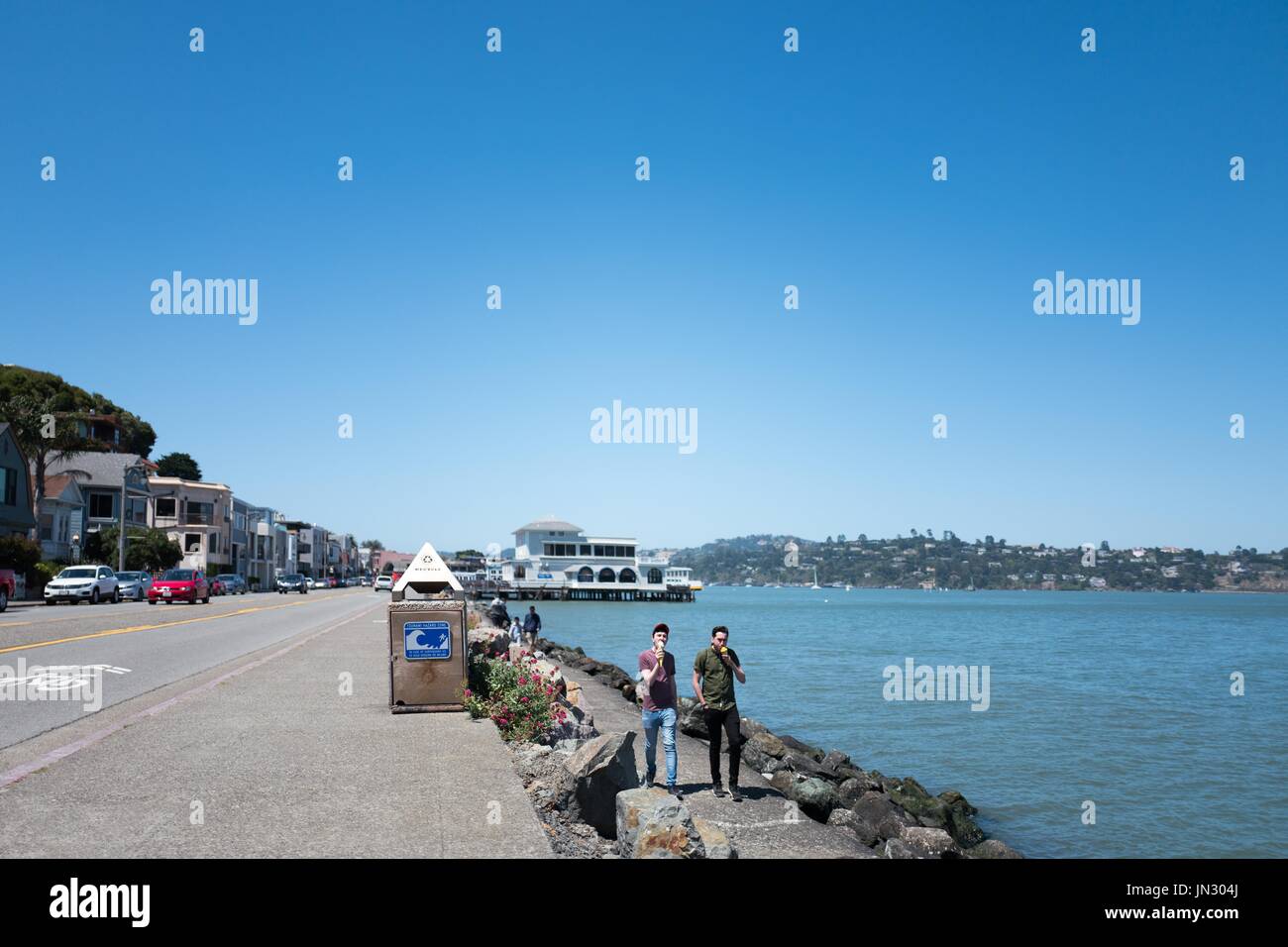 Two men walk along a seawall and eat ice cream cones on Bridgeway Road in the San Francisco Bay Area town of Sausalito, California, June 29, 2017. Stock Photo
