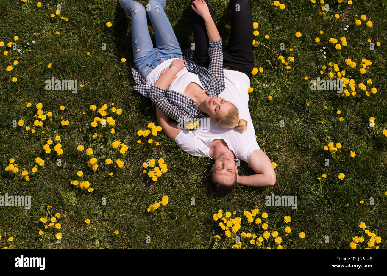 Сесть в паре. Девушка лежит на плече парня на природе. Пара лежит на траве голова к голове. Пара лежат на траве пьяные. Couple laying on grass Top view.