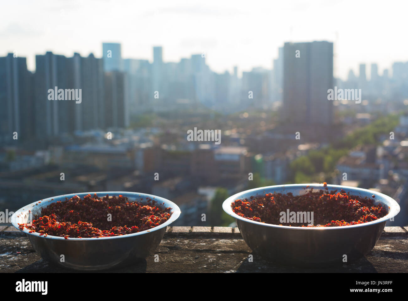 Bowls of ground red pepper drying ingredient for Sichuan sauce on a building rooftop, Chengdu, Sichuan Province, China Stock Photo
