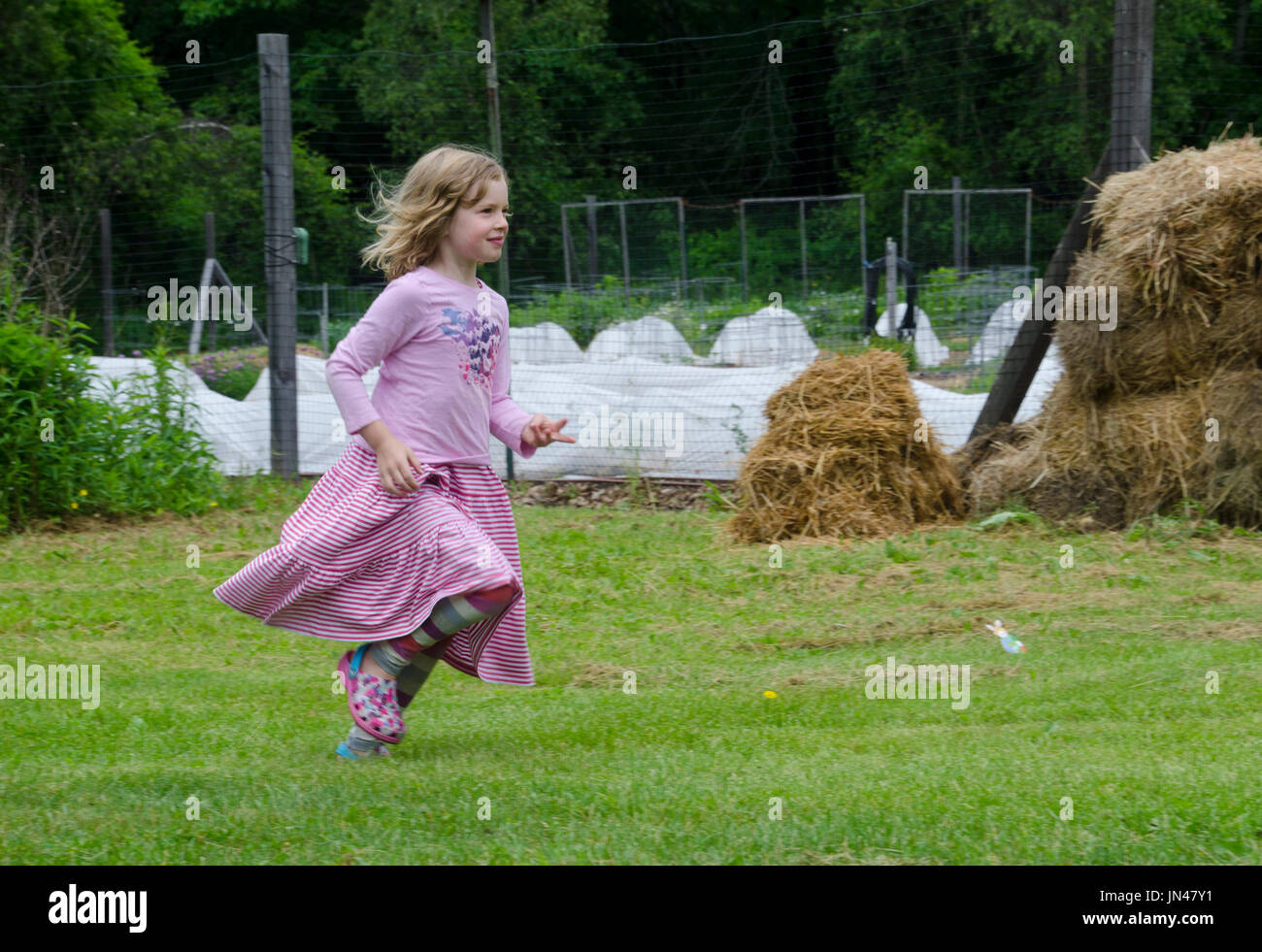 Young girl runs in the Yarmouth Community Garden, Maine, USA Stock Photo