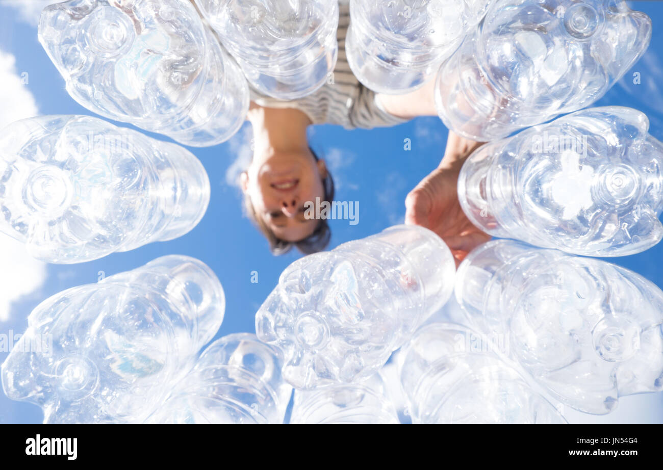 Woman recycling plastic water bottles high key looking up POV in New