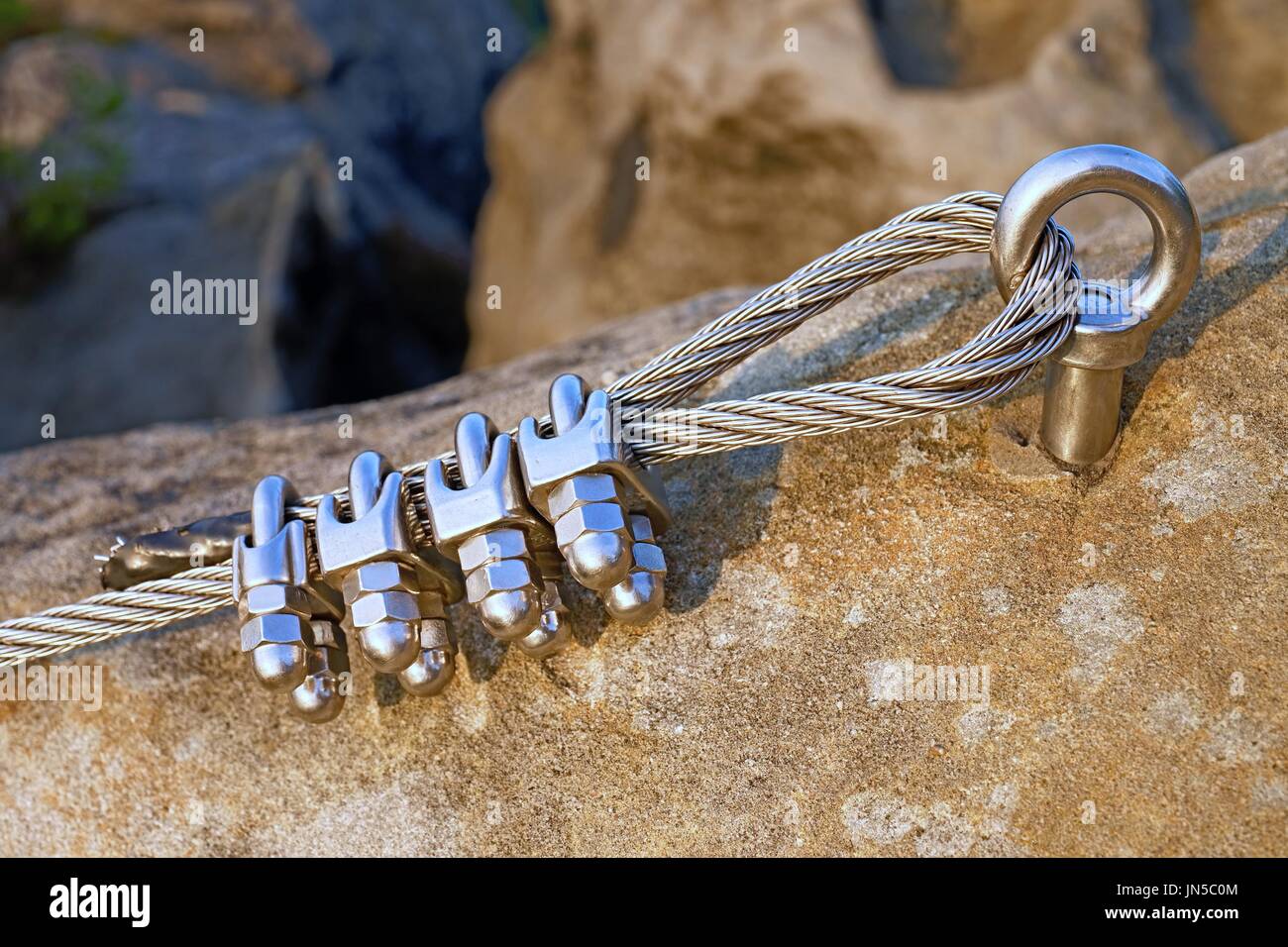 Solid knot on steel rope. Iron twisted rope fixed in block by strong screws  snap hooks. Detail of rope end anchored into rocky wall Stock Photo - Alamy