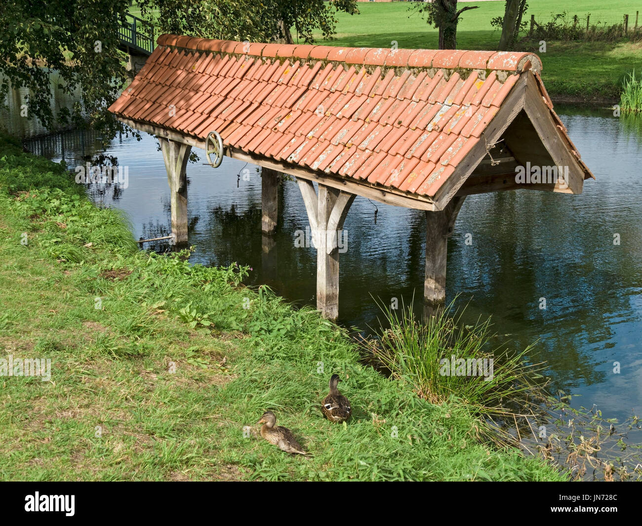 Old wooden boat house with clay tiled roof in fishpond in the grounds of Doddington Hall Estate, Lincolnshire, England, UK Stock Photo