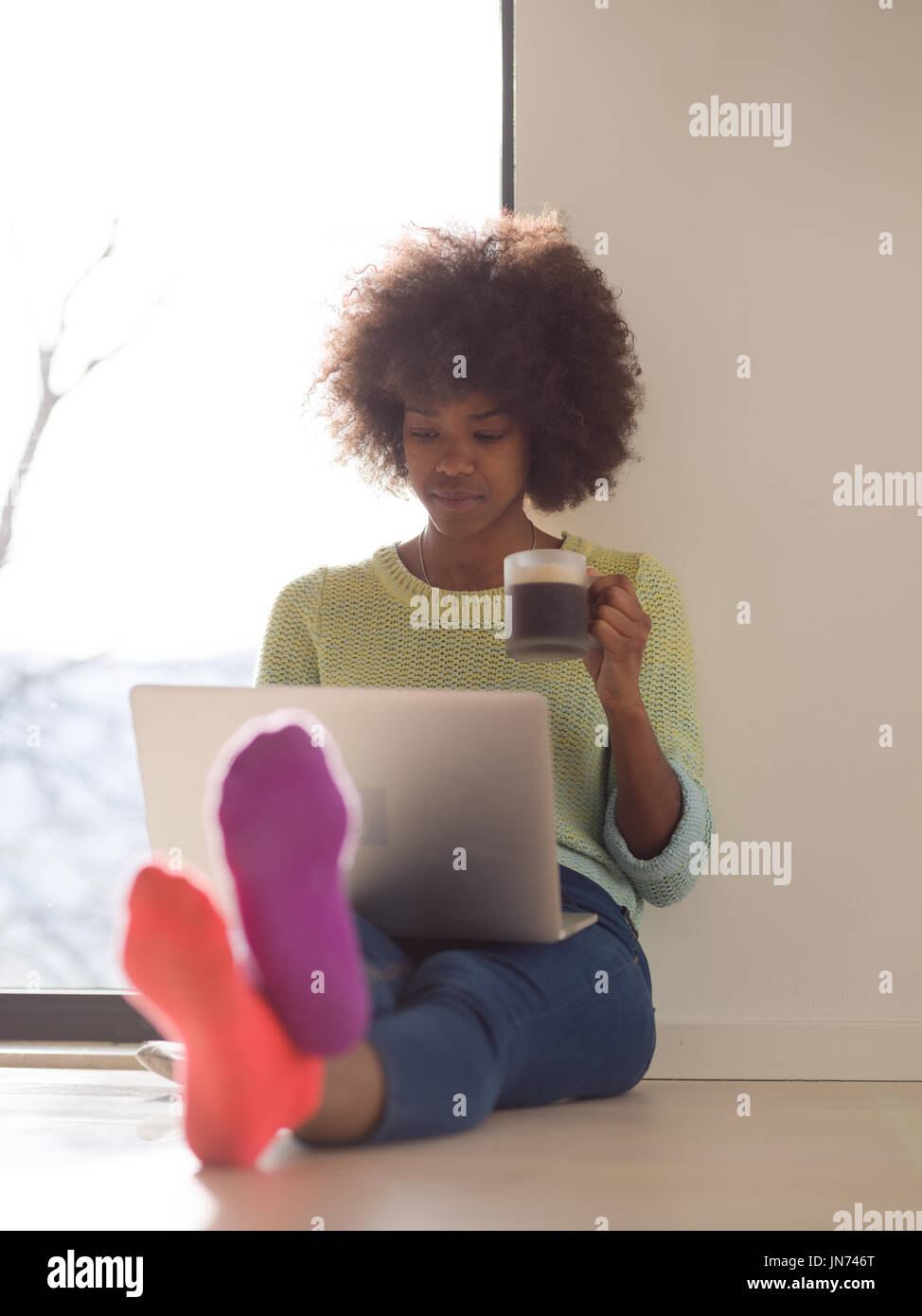 Young african american woman smiling sitting on the floor near bright ...