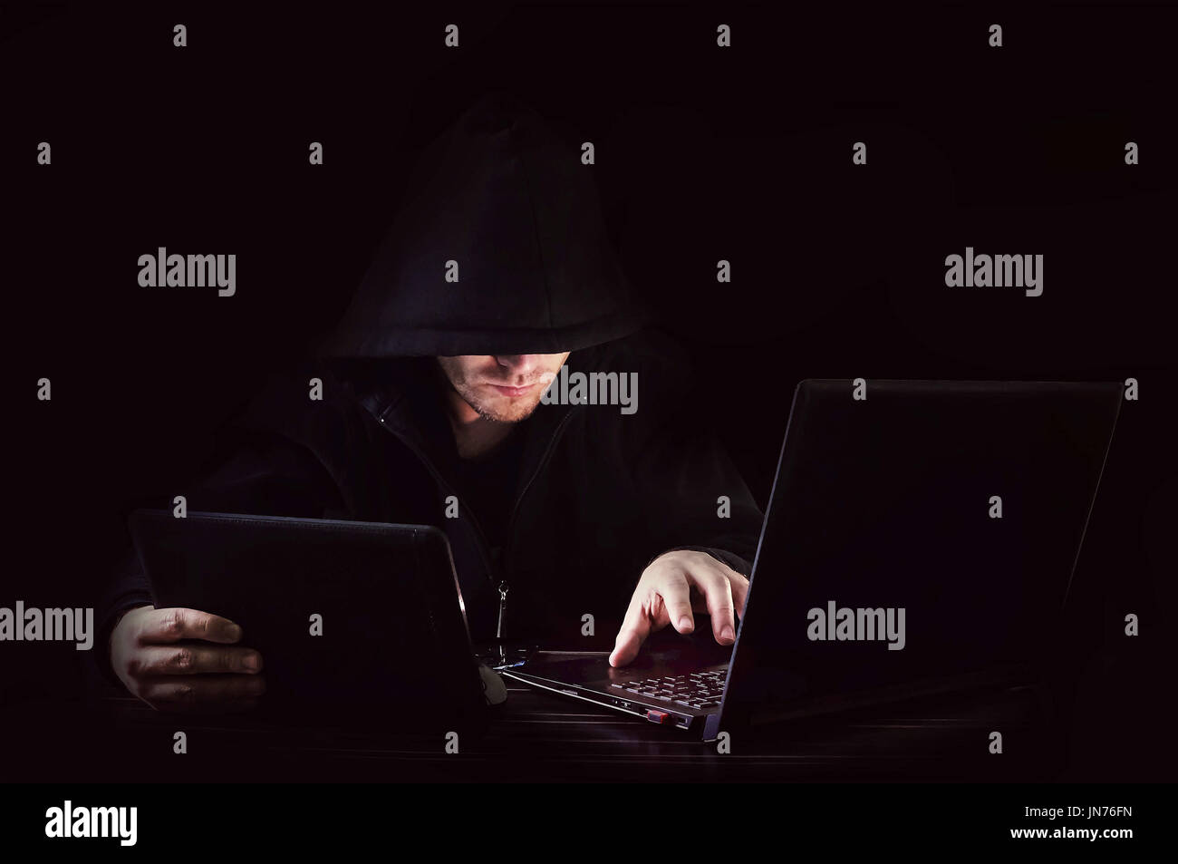 hacker a tablet and a computer on black background Stock Photo