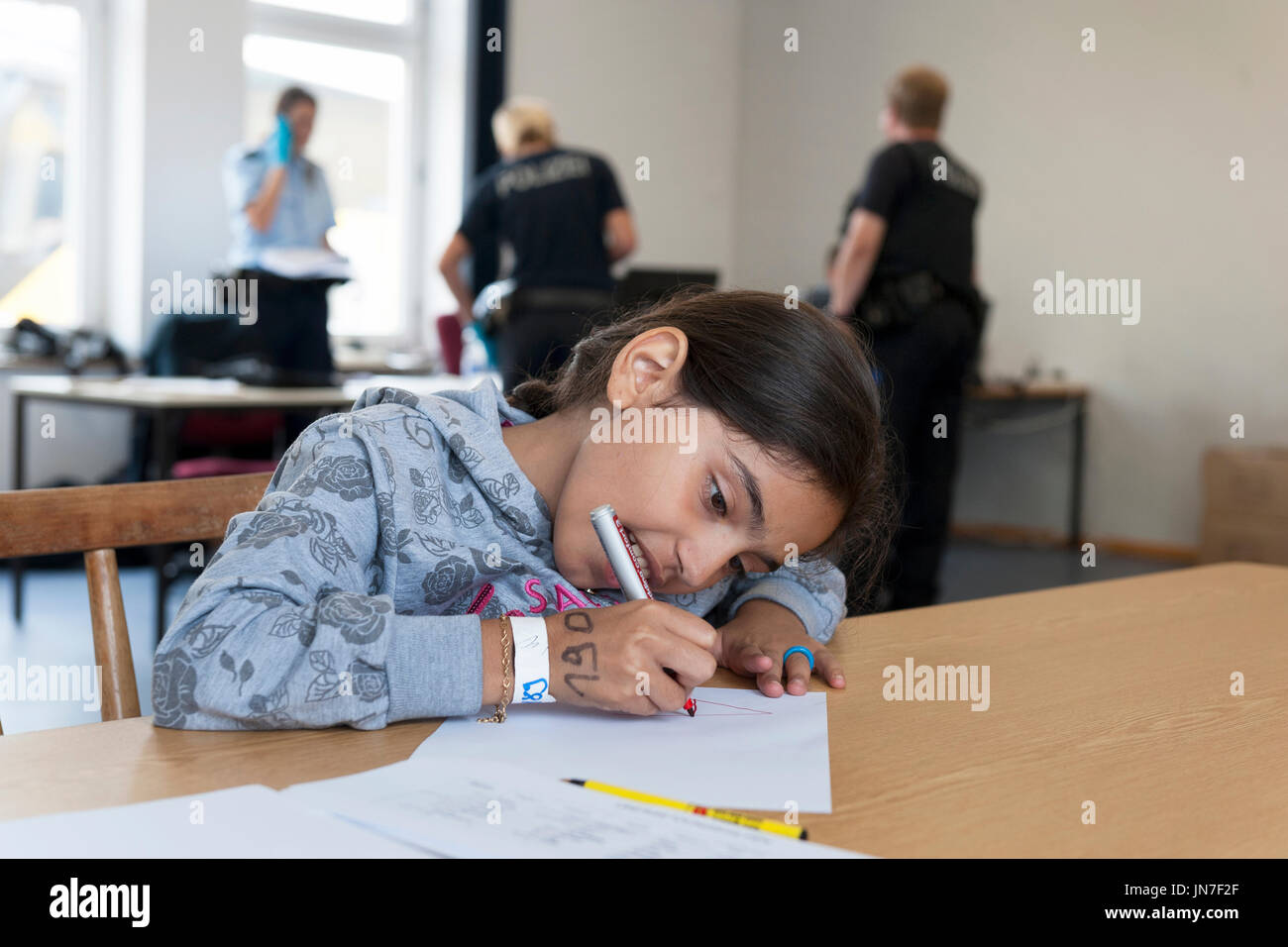 Passau, Germany - August 2, 2015 : Young refugee girl from Syria at the registration area in Passau, Bavaria. She is writing a letter. Stock Photo