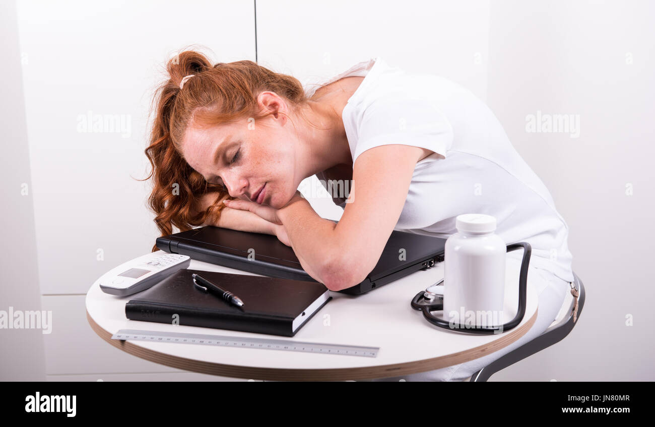 Young red-haired doctor has fallen asleep because of overworked Stock Photo