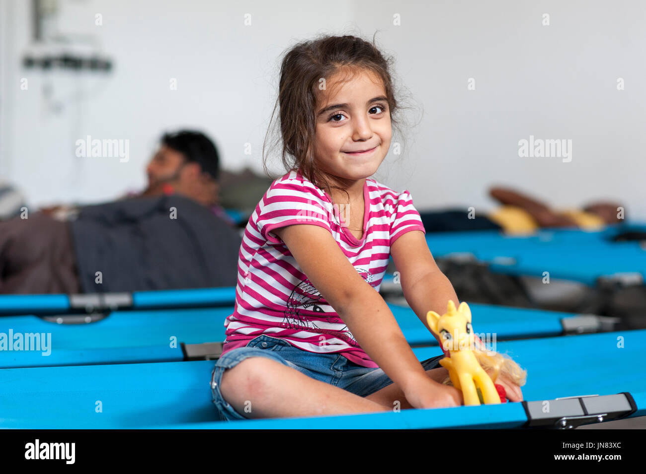Passau, Germany - August 1st, 2015: Syrian refugee girl at a camp in Passau, Germany. She is happy to arrive in safety after fleeing from civil war. Stock Photo