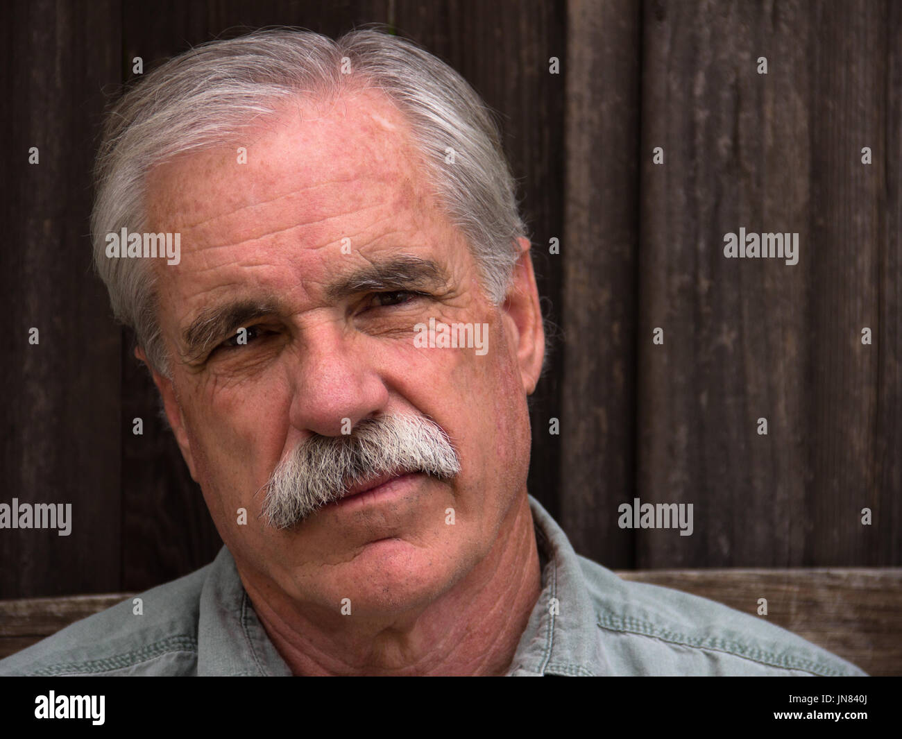 A distinguished man in a blue shirt has a serious look. Stock Photo