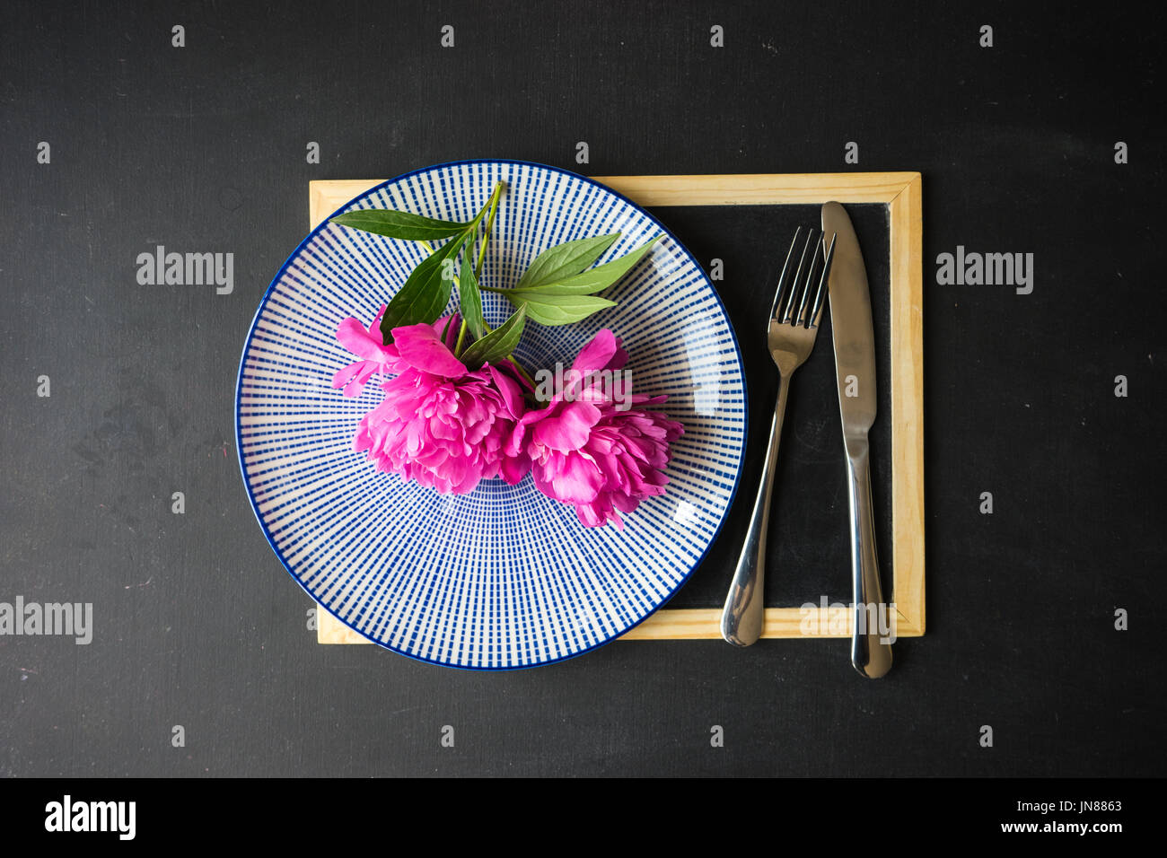 Summer table setting with bright peonies on dark rustic table with copyspace Stock Photo