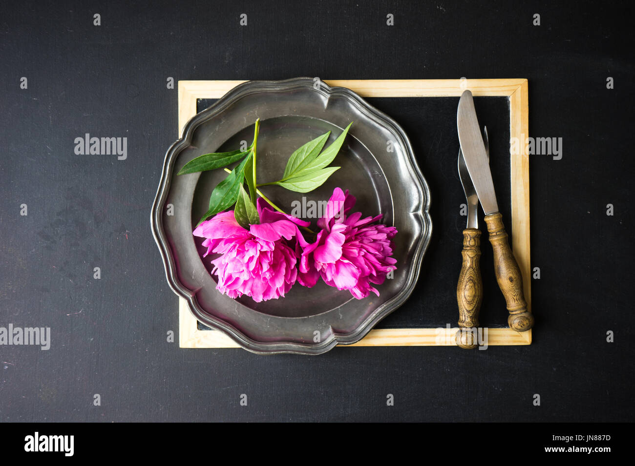 Summer table setting with bright peonies on dark rustic table with copyspace Stock Photo