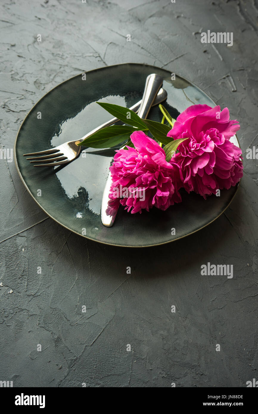 Summer table setting with bright peonies on dark rustic table with copyspace Stock Photo