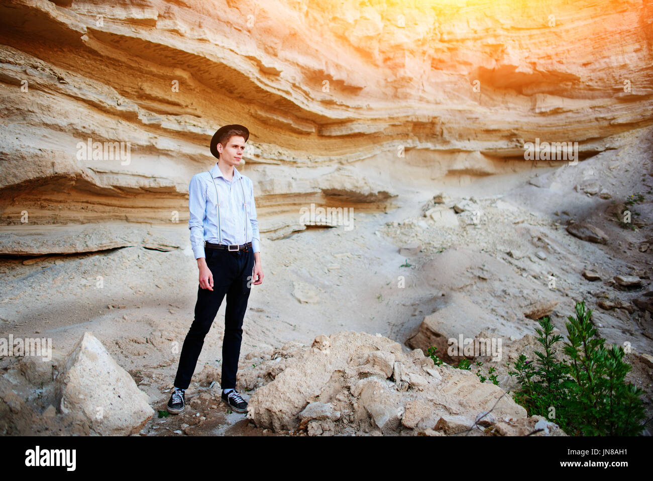 An attractive man is standing in the middle of a sand quarry and looking thoughtfully in the distance Stock Photo