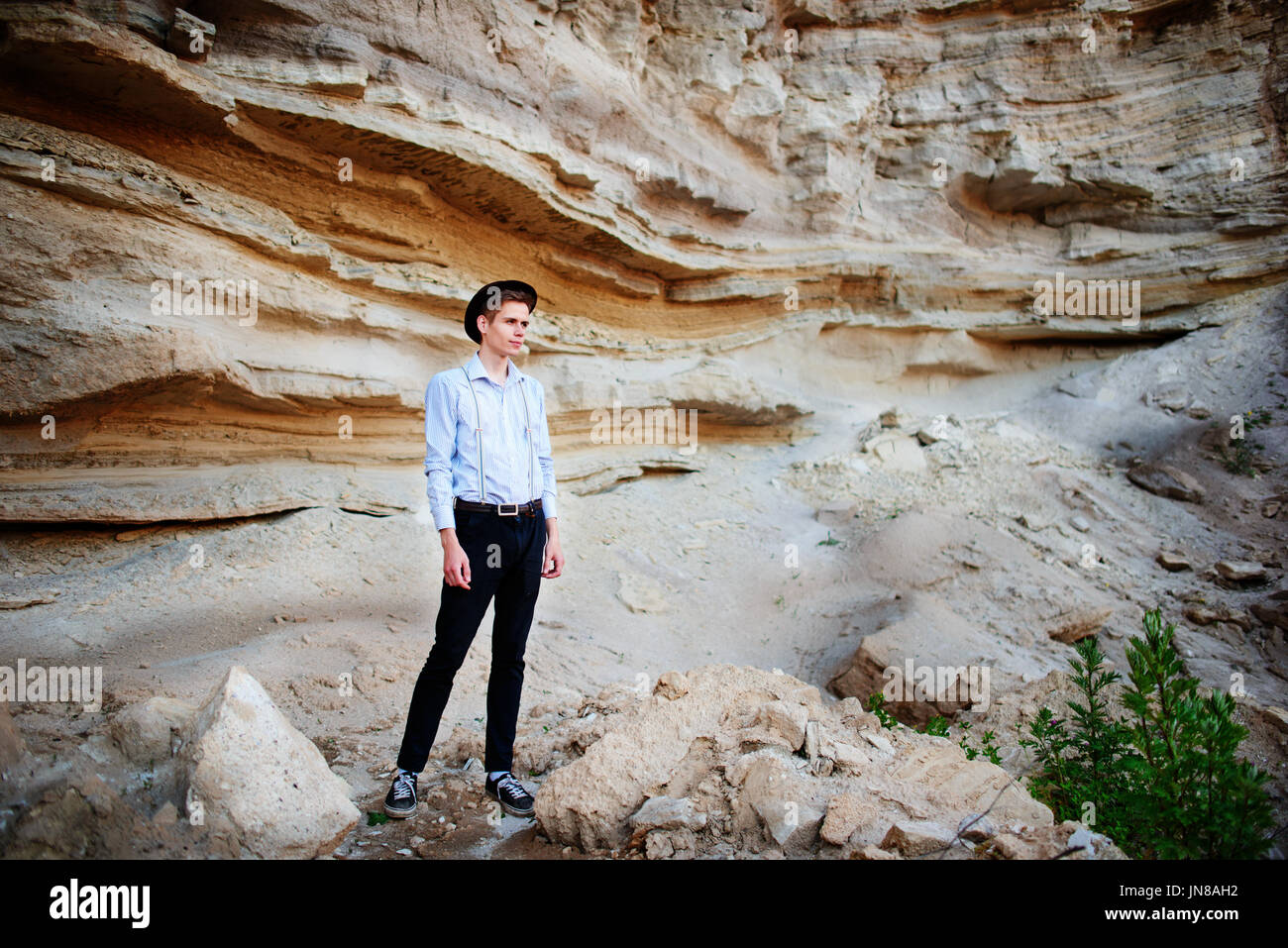An attractive man is standing in the middle of a sand quarry and looking thoughtfully in the distance Stock Photo