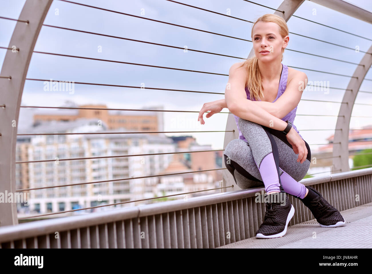 A young woman stops to relax while exercising in the City Stock Photo