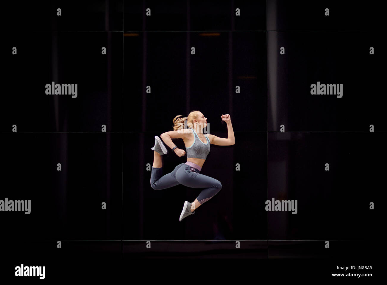 A young girl leaps into the air and strikes graceful poses in the heart of the city Stock Photo