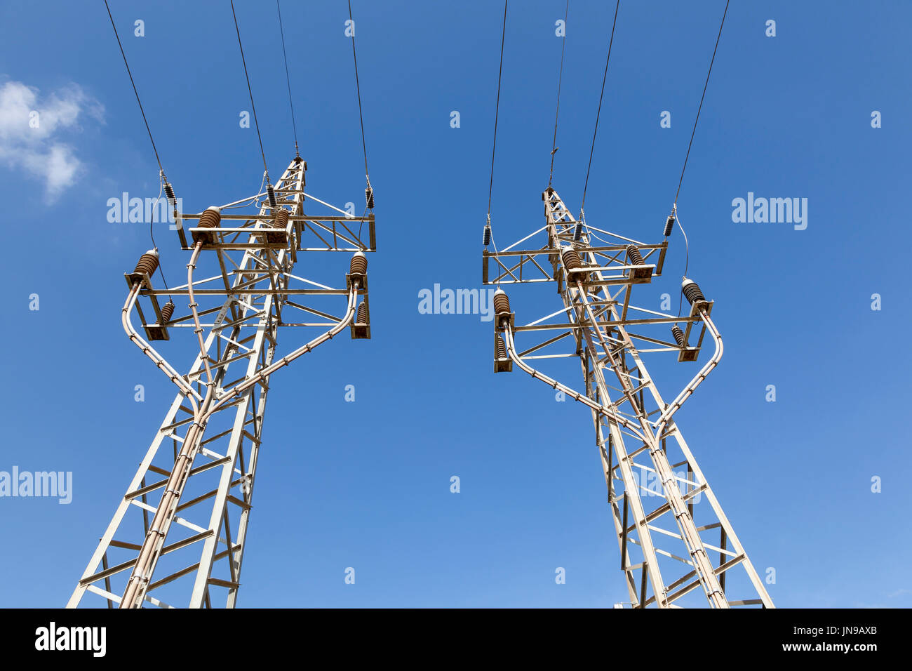 High voltage electricity poles against a blue sky Stock Photo - Alamy