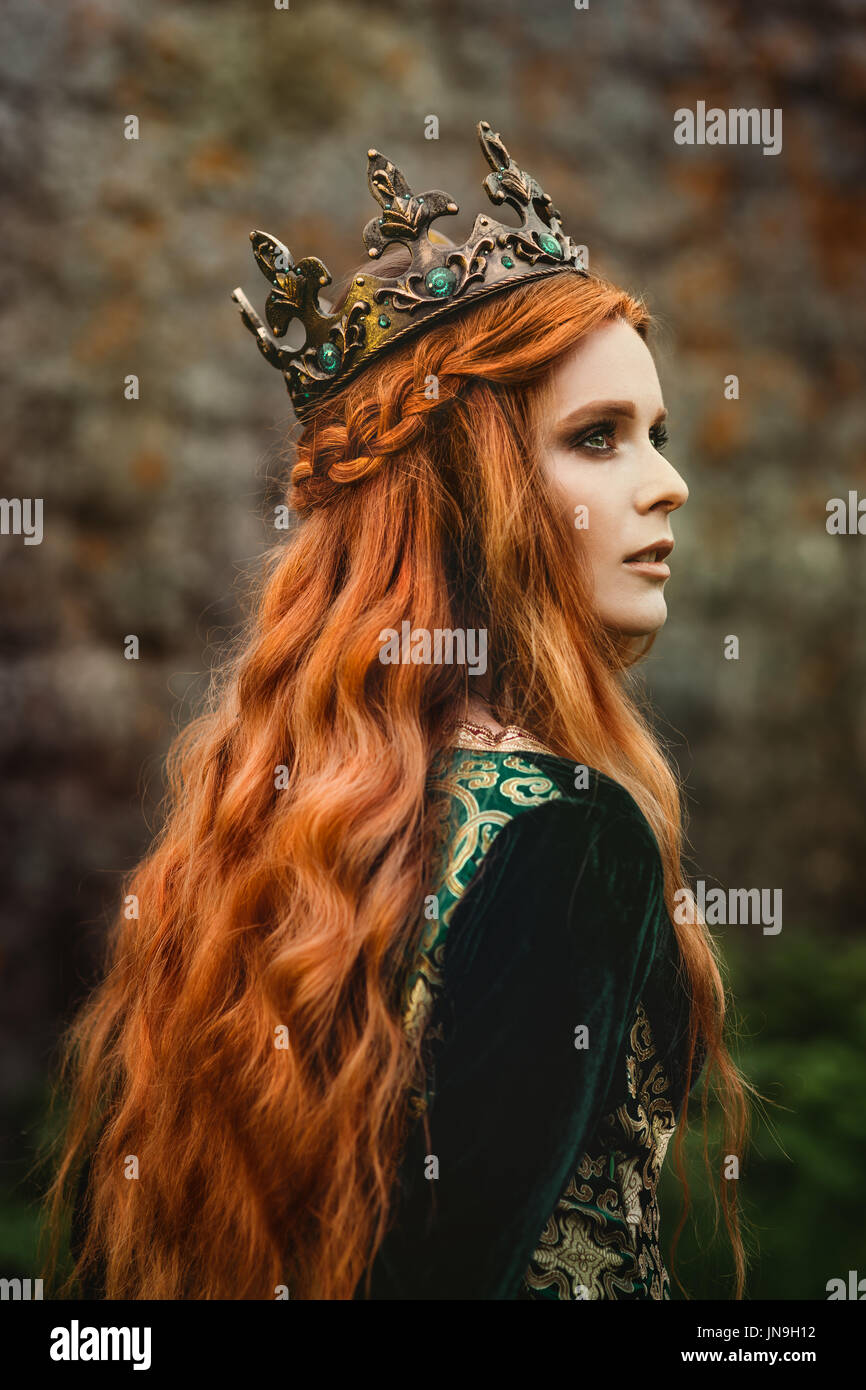 Redhaired woman in a green medieval dress near the castle Stock Photo