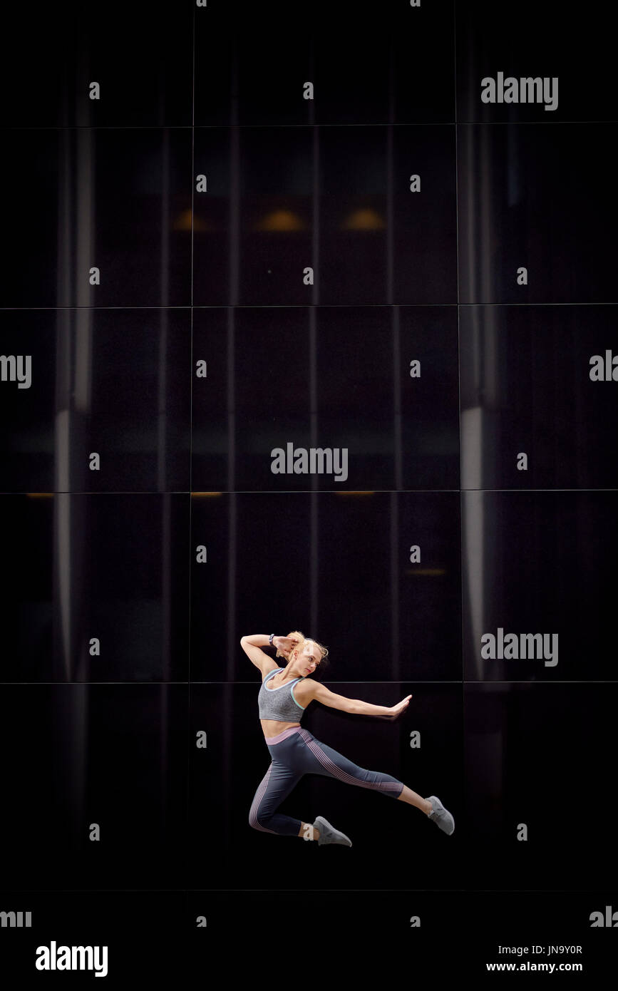 A young girl leaps into the air and strikes graceful poses in the heart of the city Stock Photo