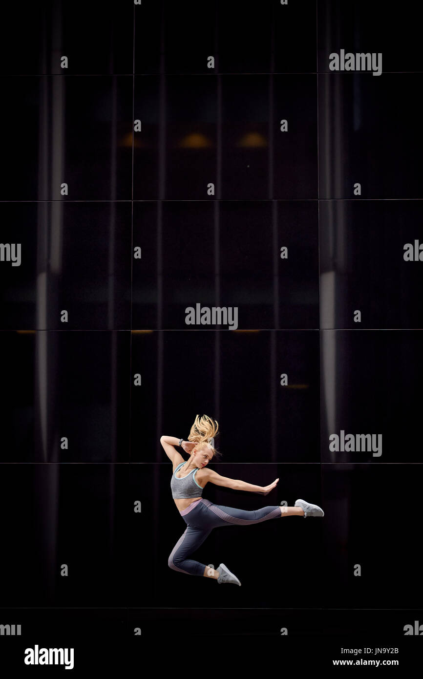 A young girl leaps into the air and strikes graceful poses in the heart of the city Stock Photo