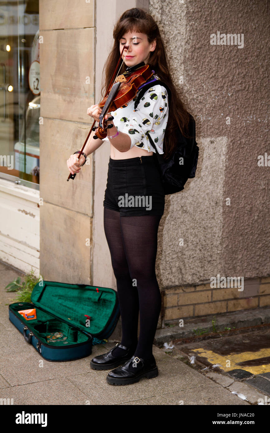 A young female student busker standing outside Thornton’s candy store playing a violin earning some money on a summers in Dundee, UK Stock Photo