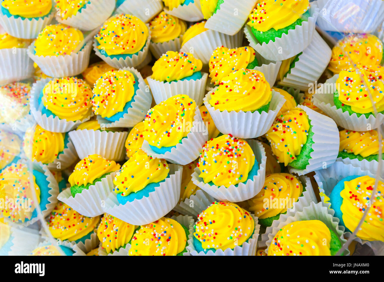 Pile of colorful homemade cakes in paper baskets with yellow cream Stock Photo
