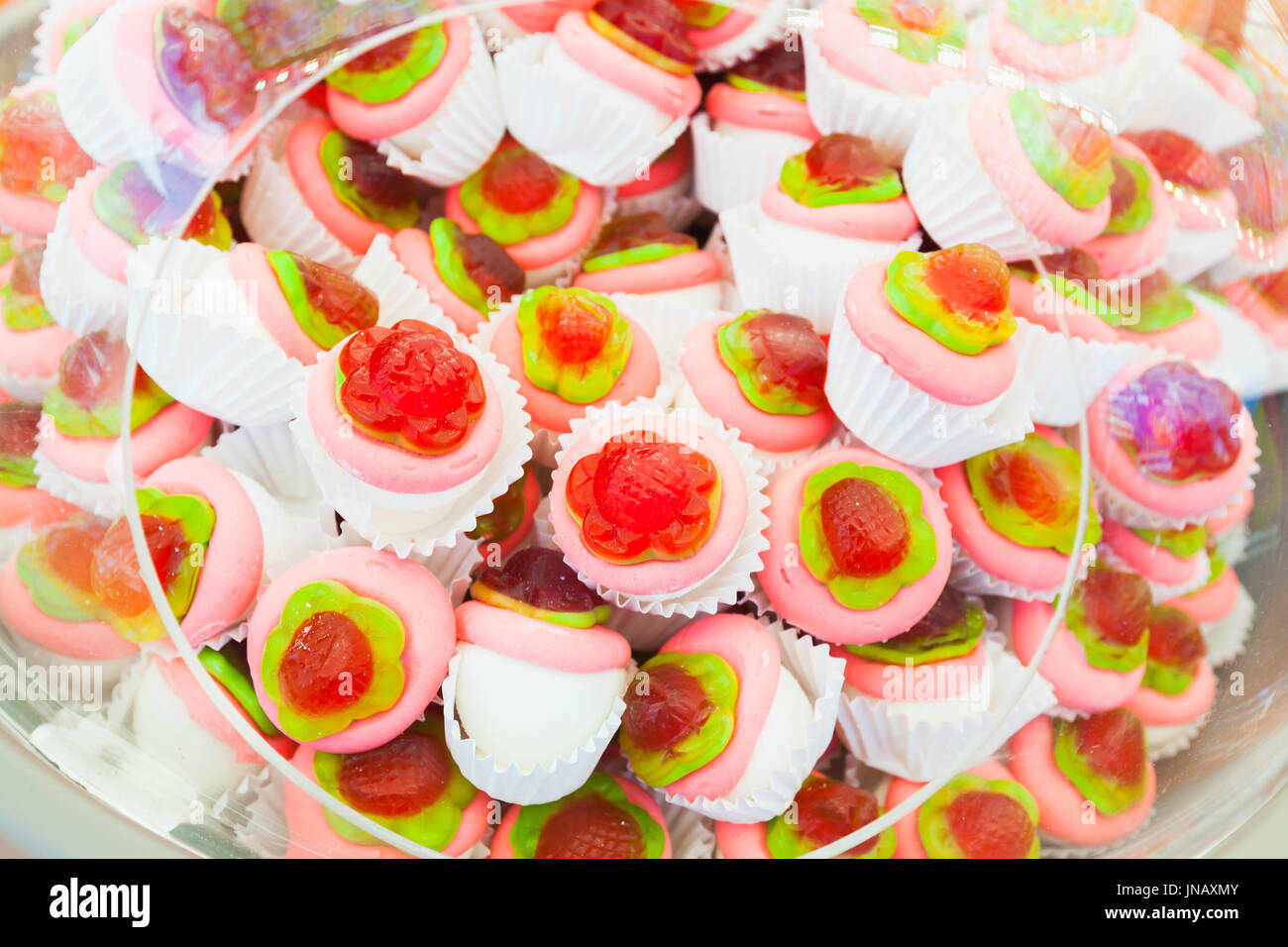 Pile of colorful homemade cakes in paper baskets with jelly flowers Stock Photo