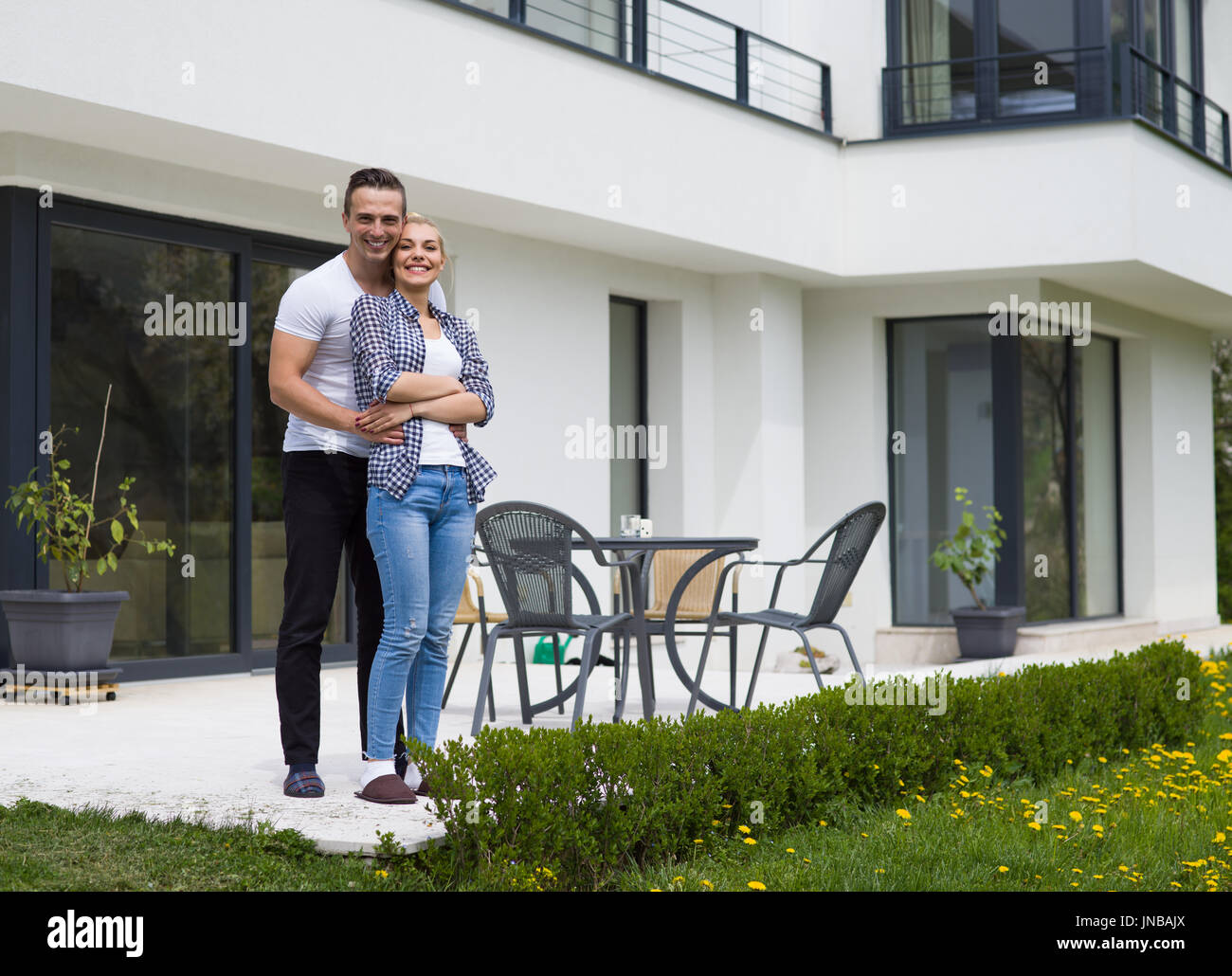 Portrait of a happy young couple hugging in front of their new luxury ...