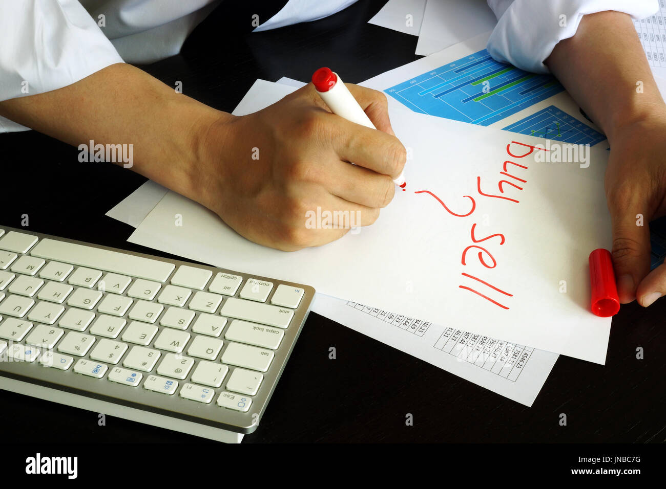 Trader is writing buy or sell in a note. Stock Photo