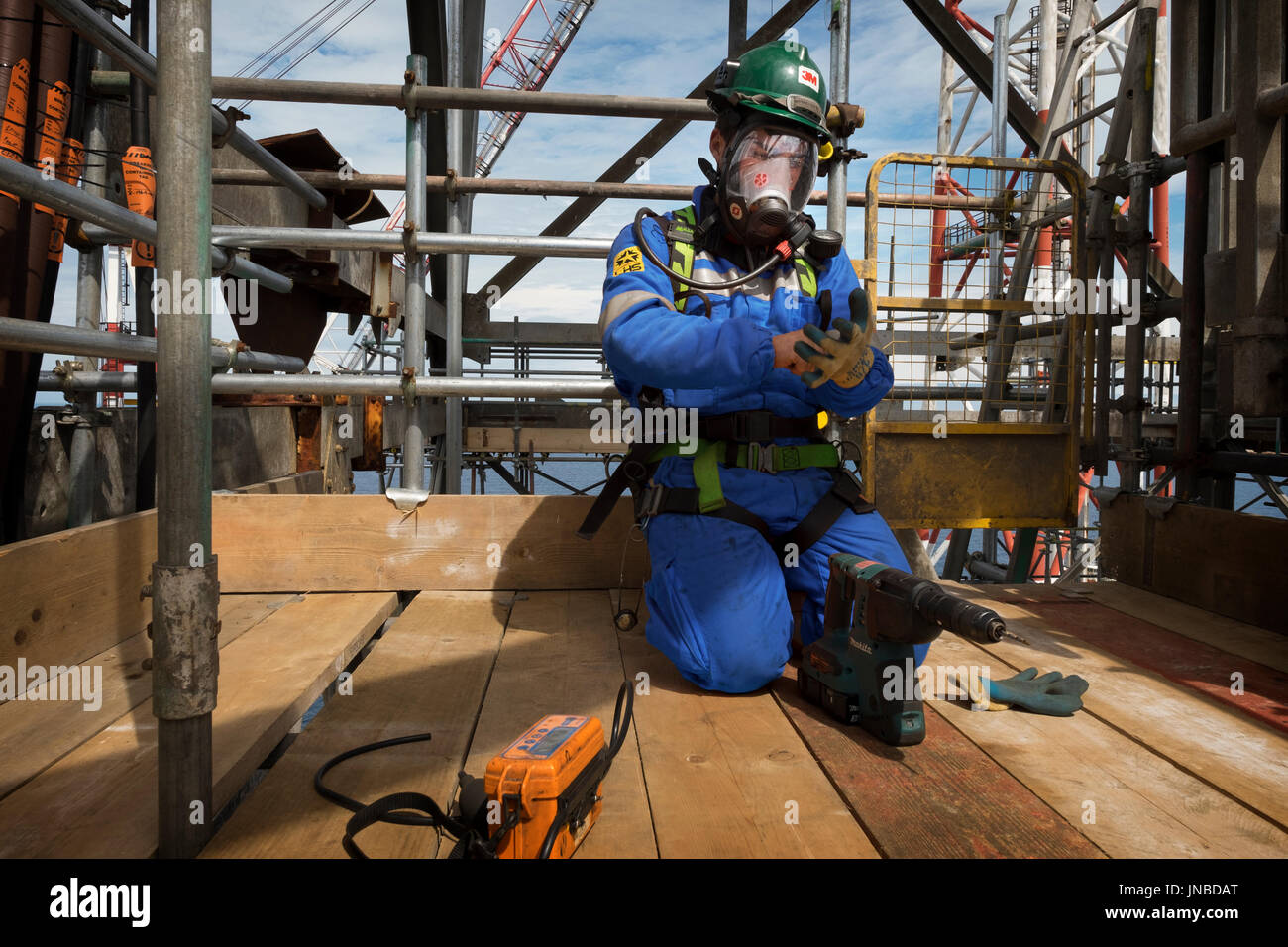 An industrial worker, wearing full breathing apparatus as about to drill into a pipe and perform a gas test. credit: LEE RAMSDEN / ALAMY Stock Photo