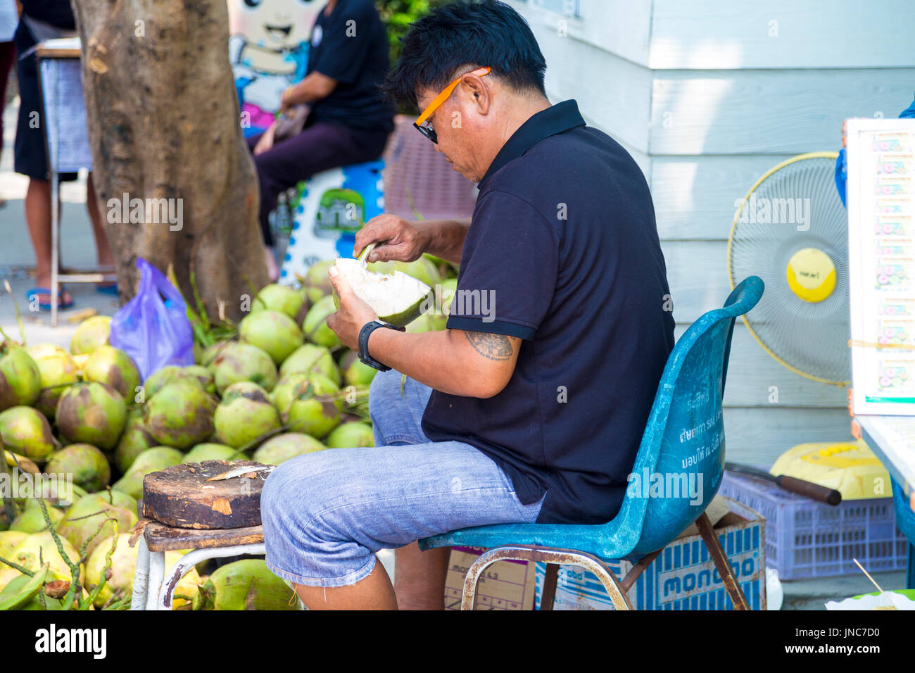 Asian man opening coconuts at Khlong Lat Mayom Floating Market, Bangkok Thailand Stock Photo